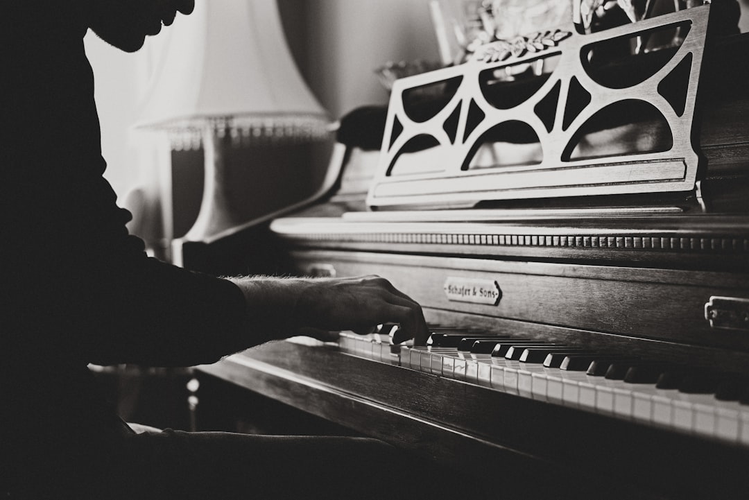 Vintage piano player by Make a Song greyscale photo of man playing spinet piano close-up photo