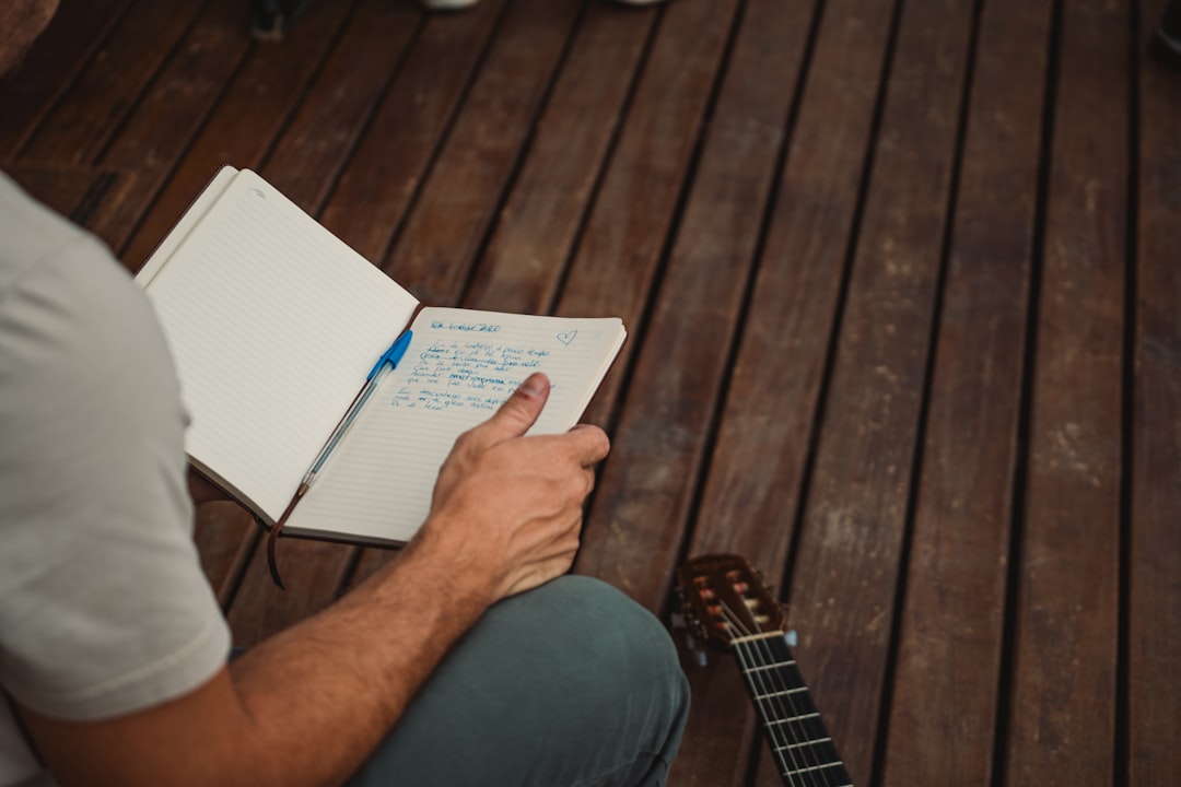 a man sitting on a wooden floor holding a notebook