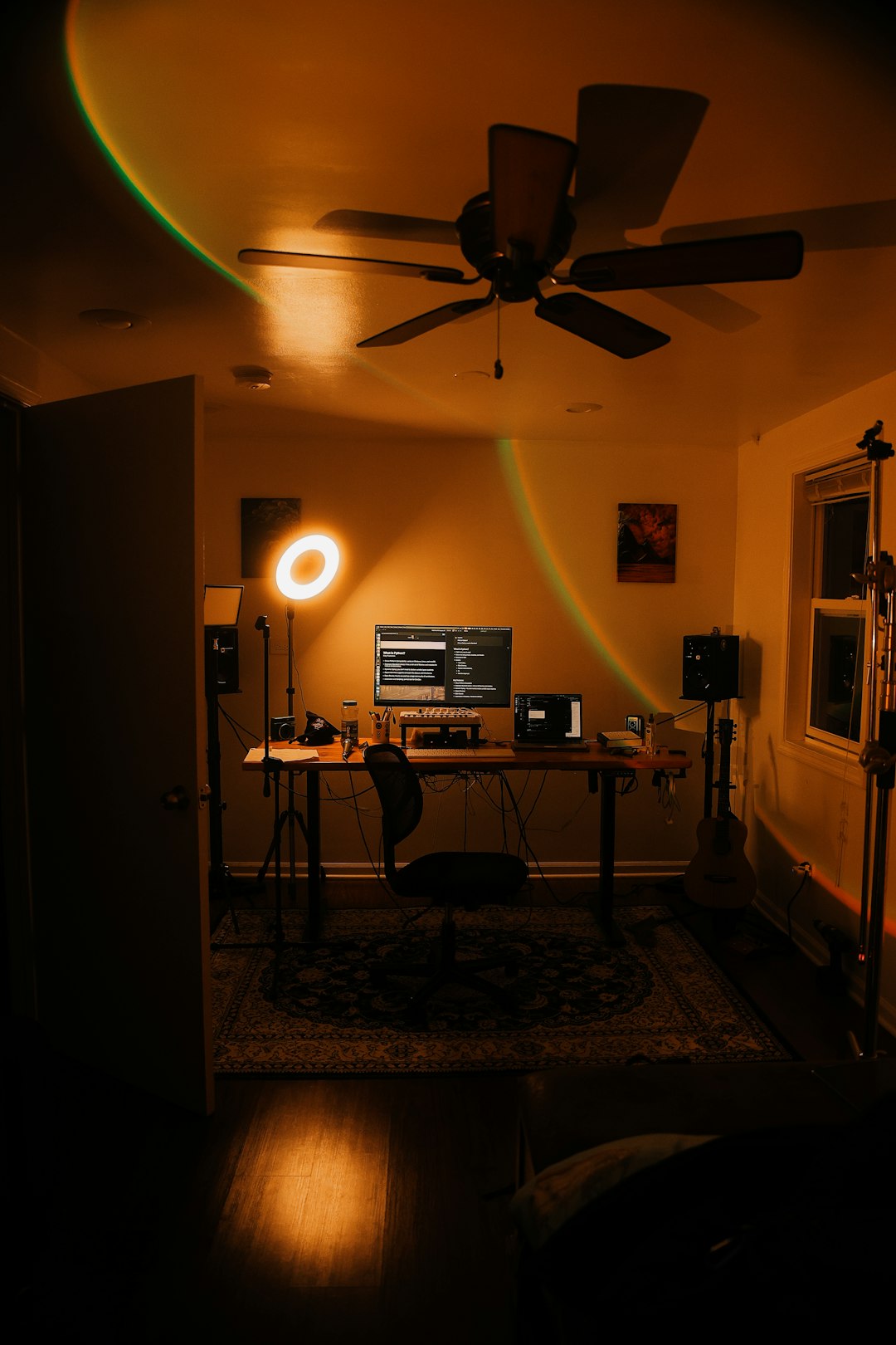 A dark room with a ceiling fan and a desk