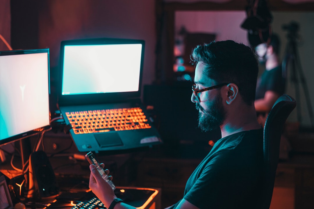 man in blue shirt wearing black framed eyeglasses using black laptop computer